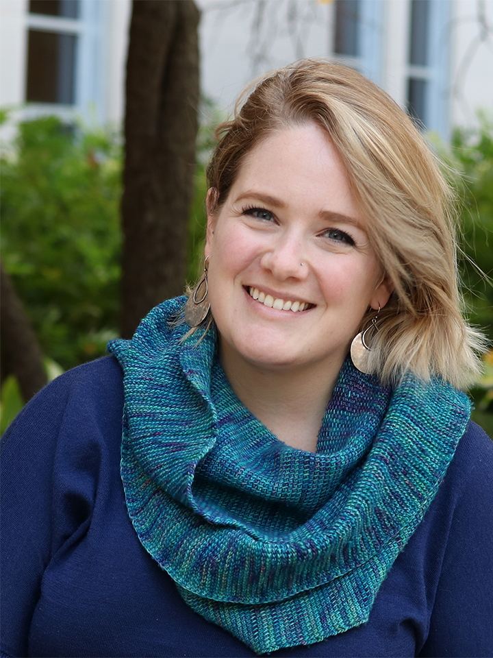 Photo of a smiling blonde woman wearing a blue shirt and turquoise scarf.