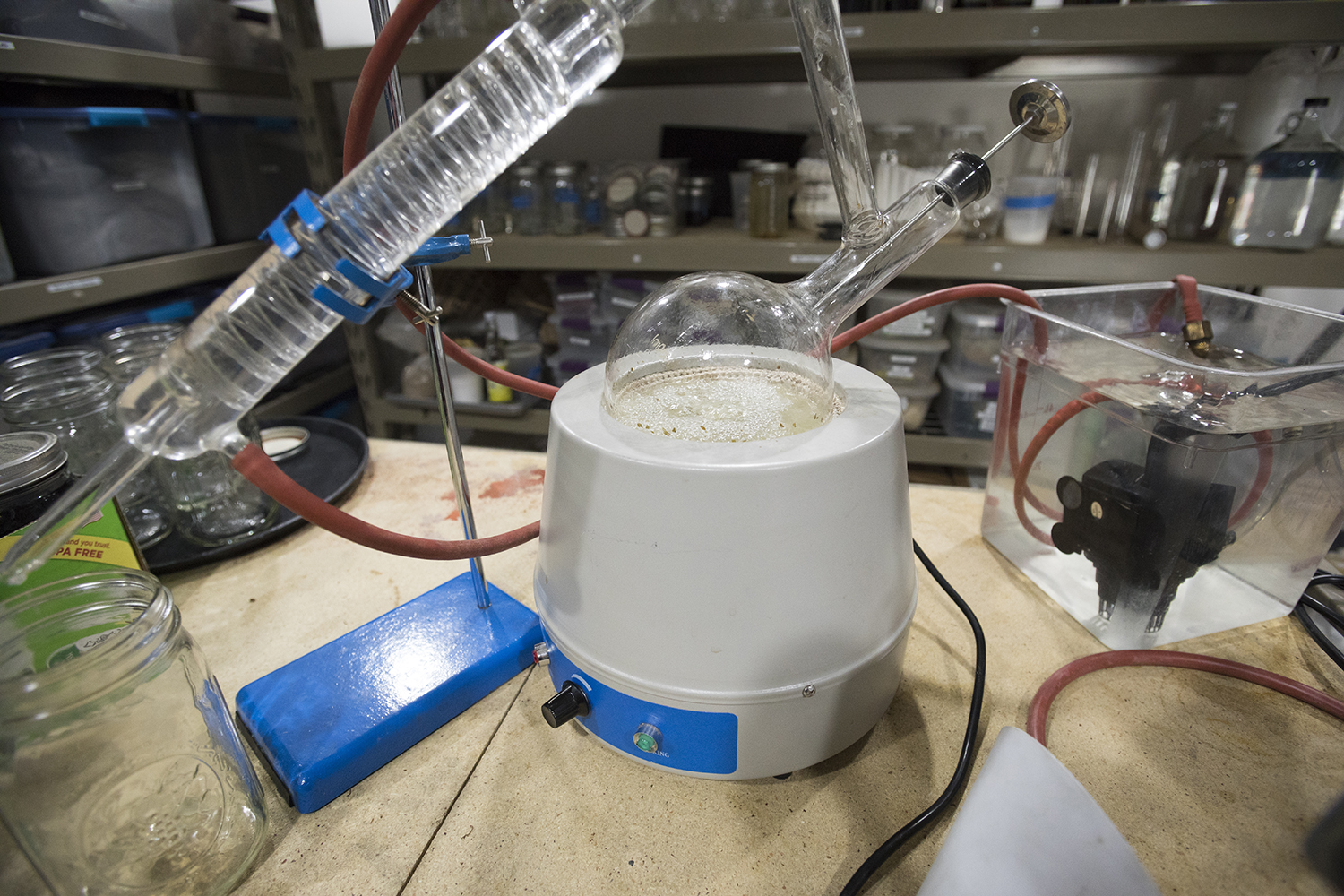 A small tabletop still with beakers and tubes and bubbling clear liquid.