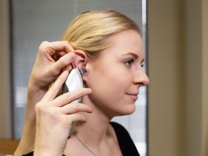 Healthcare practitioner pulling helix up and back and directing tympanic probe towards tympanic membrance